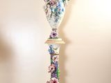 a tall vase that has a bird on top of it