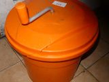 une poubelle orange posée par terre dans une salle de bains