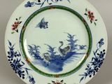 a blue and white plate with a bird and flowers on it