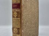 un livre marron aux bords dorés et à la couverture rouge