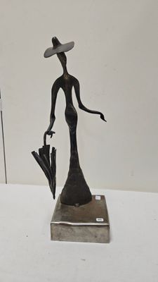 statue d'une femme avec un chapeau et un parapluie posés sur une table