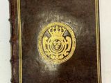 un vieux livre orné d'un sceau doré, posé sur une surface blanche
