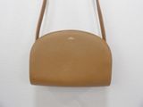 a tan purse with a long strap hanging from it ' s shoulder