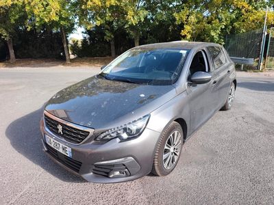 La voiture argentée est garée sur le parking près des arbres.
