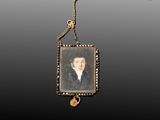 an antique portrait of a man in a black suit hangs from a gold chain
