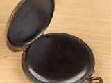 a small black pocket watch sitting on a wooden table