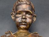 bronze statue of a boy with his hands in his pockets