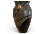 a black vase with holes in it on a white surface