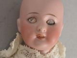 a close up of a doll with a white dress on