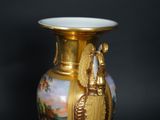 a gold vase with a painting on it on a black background