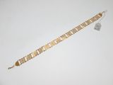gros plan d'un bracelet en or sur une surface blanche