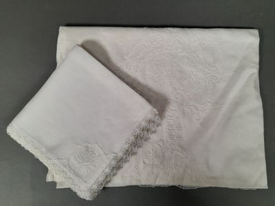 two pieces of white cloth with lace on them on a table