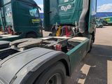 two green semi trucks parked next to each other in a parking lot