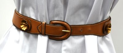 a woman wearing a white dress and a brown belt