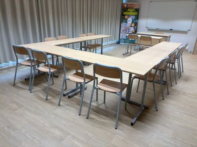 des tables et des chaises dans une salle de classe, avec un tableau noir en arrière-plan