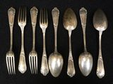 six spoons and six forks are lined up on a black surface