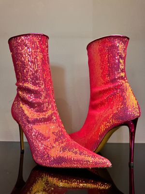 des bottes à talons hauts rouges et roses posées sur une surface réfléchissante