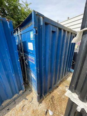 une benne bleue posée au milieu d'une cour