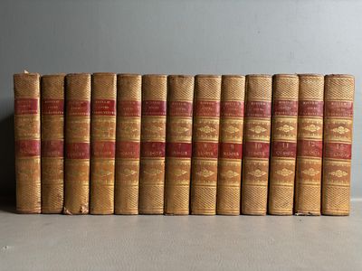 Plusieurs vieux livres sont alignés sur une étagère dans une pièce