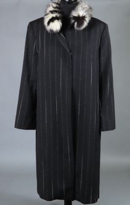 un manteau noir à col de fourrure sur un mannequin
