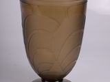 un vase en verre brun muni d'un couvercle, posé sur une surface blanche