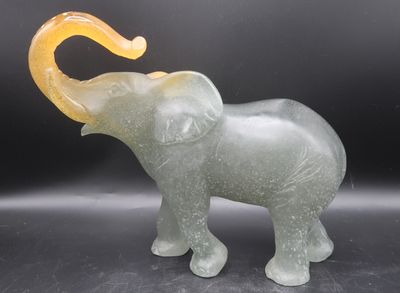 a glass elephant that is standing on a black surface