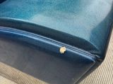 a blue leather couch with a gold button on it