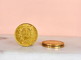 two gold coins sitting on top of a marble counter top