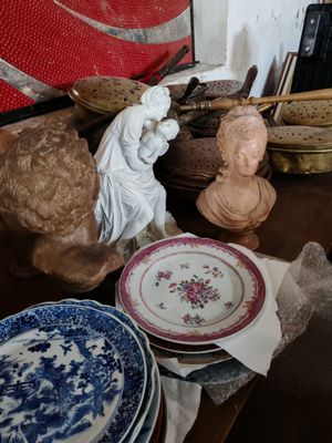 une table sur laquelle sont disposées de nombreuses assiettes et statues
