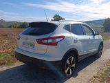 the rear end of a silver nissan suv parked on a dirt road