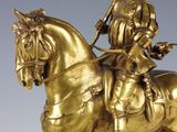 an antique bronze statue of a man riding a horse with a flag on it