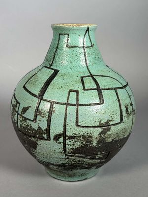 un vase vert orné de motifs noirs et blancs