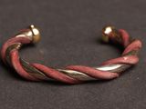 a close up of a red and gold bracelet on a black surface