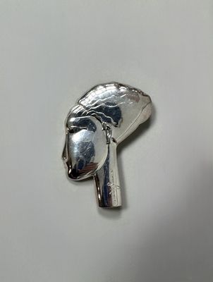 a silver object on a white surface that looks like a woman ' s head