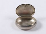 silver plated pill case with lid open on a white surface