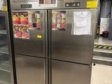 Des réfrigérateurs en acier inoxydable sont alignés dans un magasin, leurs portes ouvertes.