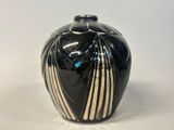 un vase noir et blanc posé sur une surface blanche