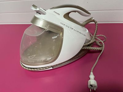 a white and silver steam iron sitting on a pink table