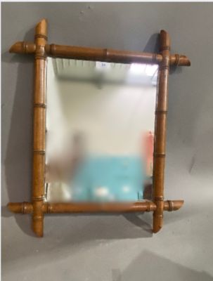 a mirror hanging on the wall with a bamboo frame