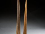 une paire de sculptures en bois posées sur des socles, sur fond noir