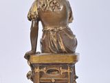 bronze statue of a woman sitting on a table with a book