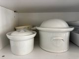 a white crock pot and a white crock pot on a shelf