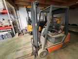 a forklift in a garage with a lot of tools