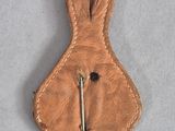 brown leather key case with a pin in it on a white surface