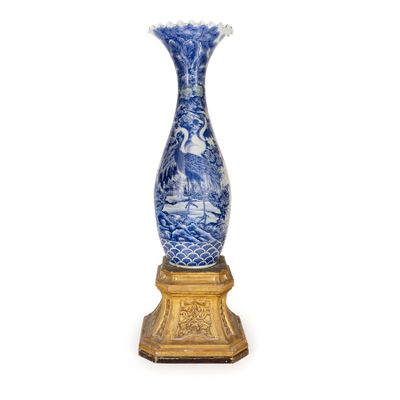 un vase bleu et blanc posé sur un socle doré