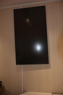 une télévision à écran plat fixée au mur au-dessus d'un lit