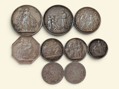six pièces d'argent de tailles et de formes variées sont disposées sur une surface blanche