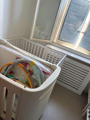 un lit de bébé dans une chambre avec une fenêtre et un radiateur
