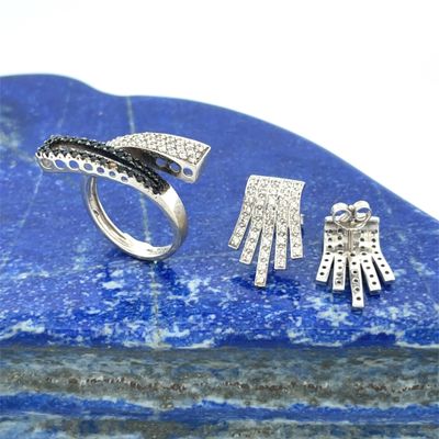 two pieces of silver jewelry sitting on top of a blue stone