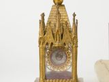a gold clock sitting on a table next to a roll of paper